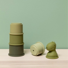 Trixie green stacking cups toy set with dinosaur figure, shown separated on a light wooden surface