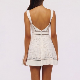 Model wearing House of CB white mini dress with lace embroidery, low open back, and thick straps, back view