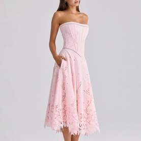 Model wearing House of CB pink strapless corset midi dress with floral lace skirt overlay and side pockets