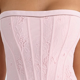 Model wearing House of CB pink strapless corset top with floral broderie anglaise embroidery and boned panelling detail