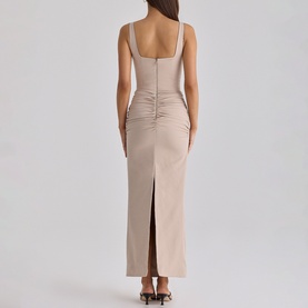Model wearing House of CB taupe ruched maxi dress with square neckline, sleeveless design, and back split, styled with strappy heels.