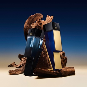 Carolina Herrera EDP duo in navy blue and midnight black with gold lettering, displayed on driftwood against a deep blue background