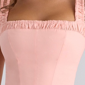 Model wearing House of CB peach top with ruched elasticated neckline and structured bodice detailing, close-up view