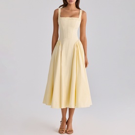 Model wearing House of CB lemon midi dress with square neckline, wide straps, fitted bodice and full pleated skirt, styled with strappy heeled sandals