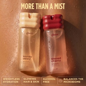 Gisou Honey Dewy and Glazed Cherry Body Mists in gold-toned bottles with cream and red caps, shown side by side