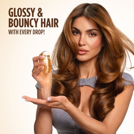 Model with Gisou Hair Oil, holding small gold bottle, showcasing glossy bouncy hair results