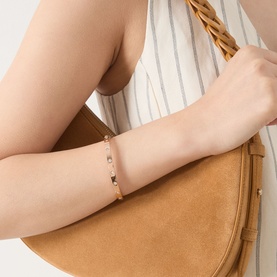 Model with Kate Spade Set In Stone Hinged Bangle in rose gold-tone with clear crystal stud embellishments, styled with tan suede bag.