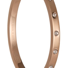 Kate Spade bangle in rose gold-tone plated metal with evenly spaced clear crystal embellishments and engraved branding