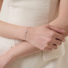 Model with Kate Spade Bow Charm Bracelet in silver-tone, dainty chain with bow and Spade charms, diamant&eacute; detail, on wrist