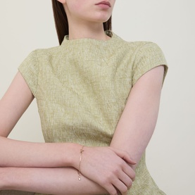 Model with Kate Spade Bow Charm Bracelet in gold-tone, dainty chain with bow and Spade charms, diamant&eacute; detail, styled with sage green dress
