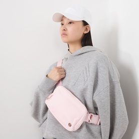 Model with Lululemon Classic Ball Cap in White, styled with grey hoodie and pink crossbody belt bag