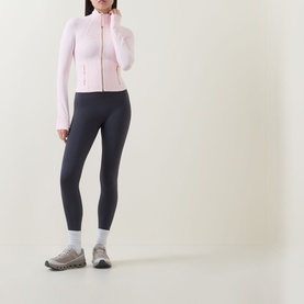 Model wearing Lululemon Pink Pearl zip-up jacket with navy leggings, white ankle socks and grey trainers.