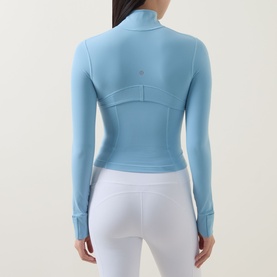 Model wearing Lululemon Seafoam jacket, rear view, cropped fit with mock neck and thumb holes, styled with white leggings