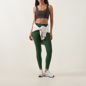 Model wearing Lululemon Ivy Grove leggings, styled with a grey sports bra, white hoodie tied at waist, and white trainers.