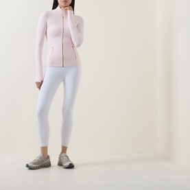 Model wearing Lululemon Pink Pearl zip-up jacket with white leggings and grey trainers.