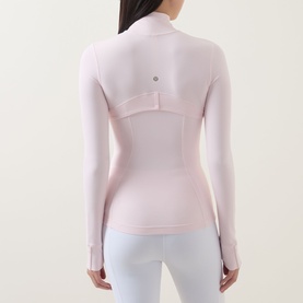 Model wearing Lululemon Pink Pearl jacket, back view, with white leggings. Form-fitting with long sleeves and thumbholes.
