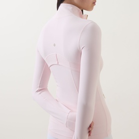 Model wearing Lululemon Pink Pearl zip-up jacket with thumb holes, shown from rear three-quarter angle, styled with matching pink leggings