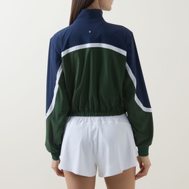 Model wearing Lululemon Court Champ UV-Protective Tennis Jacket in White/Ivy Grove/Club Blue, styled with white shorts, back view.