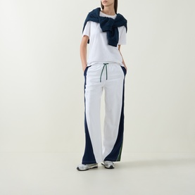 Model wearing Lululemon white, navy and green wide-leg trousers with drawstring waist, styled with white tee and navy scarf.