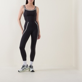 Model wearing Lululemon black and light ivory leggings with matching crop top, styled with white socks and multicolour trainers.