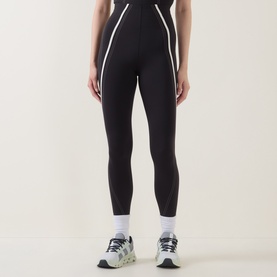 Model wearing Lululemon black leggings with light ivory contrast piping, styled with white ankle socks and grey chunky trainers.