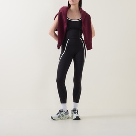 Model wearing Lululemon black and light ivory leggings with white side stripes, styled with a burgundy zip-up hoodie and grey trainers.