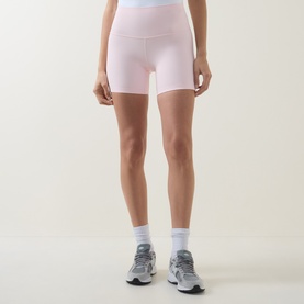 Model wearing Lululemon Pink Pearl bike shorts, styled with white ankle socks and grey trainers
