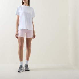 Model wearing Lululemon Pink Pearl shorts with white oversized tee, white socks and grey trainers.