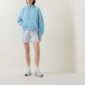 Model wearing Lululemon Heathered Core Ultra Light Grey shorts, styled with a light blue hoodie and white trainers.