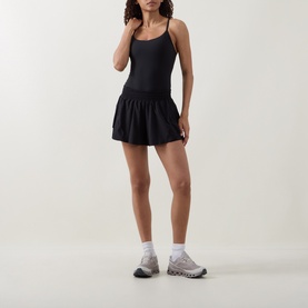 Model wearing Lululemon black tennis dress with built-in shorts, styled with white ankle socks and grey trainers