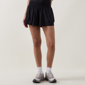 Model wearing Lululemon black shorts with elasticated waistband, styled with white socks and grey trainers.