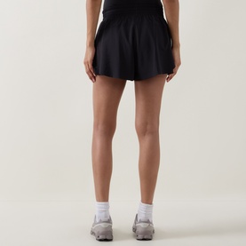 Model wearing Lululemon black shorts, styled with white ankle socks and grey trainers, rear view.