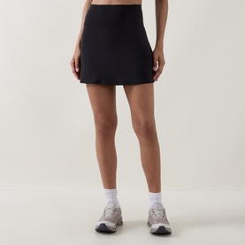 Model wearing Lululemon black mini skirt, styled with white ankle socks and grey trainers.