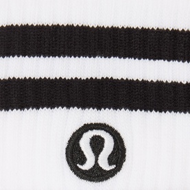 Lululemon white socks with black stripe detail and embroidered logo, close-up of knit texture and branding