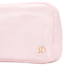Lululemon Pink Pearl pouch with rose gold logo badge, smooth nylon exterior and zip-top closure, close-up detail shot