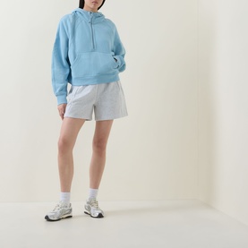 Model wearing Lululemon seafoam oversized hoodie with grey shorts and white trainers