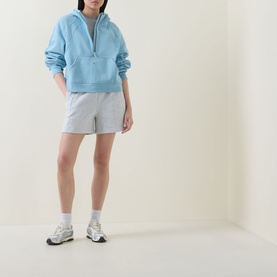 Model wearing Lululemon Seafoam half-zip sweatshirt with grey shorts and white socks with chunky trainers.