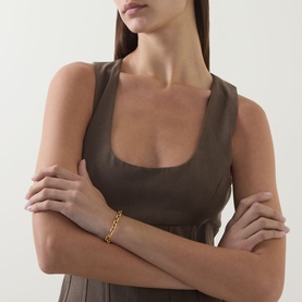 Model wearing Odd Muse Cinched Pleated Dress in Mushroom, scoop neckline, sleeveless boned bodice, styled with a gold chain bracelet.