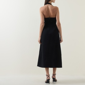 Model wearing Odd Muse Cinched Halter Dress in black, showing open back, halter neckline and midi-length skirt. Styled with black strappy heels.