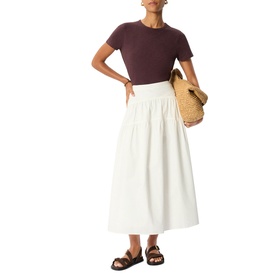 Model wearing Whistles red short-sleeve fitted tee with white midi skirt and black sandals, carrying woven bag