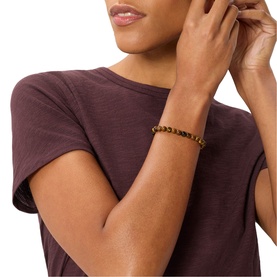 Model with Whistles red beaded stretch bracelet, worn on wrist, styled with dark mauve short-sleeve tee