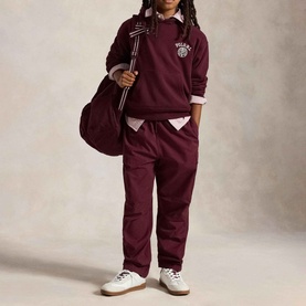Model wearing Ralph Lauren Big Fit Crest Logo Fleece Hoodie in Rich Ruby, styled with matching joggers, pink shirt, and white trainers, carrying a