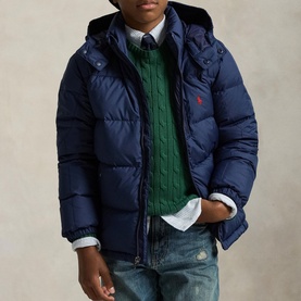 Model wearing Ralph Lauren Newport Navy hooded puffer jacket, styled with green cable-knit jumper, shirt and jeans