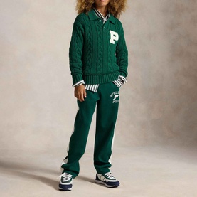 Model wearing Ralph Lauren Letter Logo Cable Knitted Sweater in green with matching joggers, striped shirt collar visible, and navy trainers.
