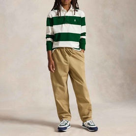 Model wearing Ralph Lauren Iconic Pony Logo Striped Rugby Shirt in cream and green, styled with tan trousers and navy trainers.