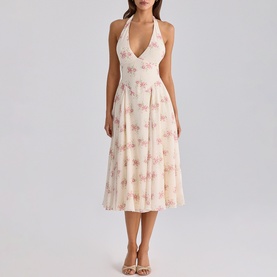 Model wearing cream halterneck midi dress with pink floral print, deep V-neckline, and full pleated skirt, styled with nude heeled sandals