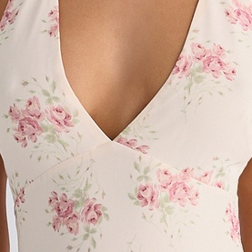 Model wearing cream floral wrap-style top with pink rose print and V-neckline, close-up detail shot