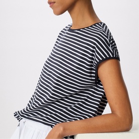 Model wearing Whistles blue and white stripe short sleeve T-shirt, relaxed fit, shown from side angle with white trousers.