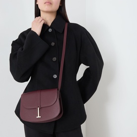 Model carrying Tom Ford Kara Small Crossbody Bag in Lost Cherry grained leather with gold-tone hardware and signature T embellishment, worn crossbody