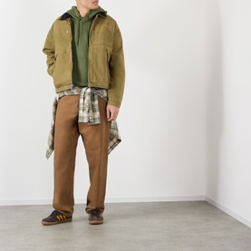 Model wearing Vans brown cotton casual jacket with olive hoodie, plaid shirt tied at waist, and tan trousers